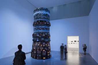 Man looking at a tall tower of old electronics in a blue lit room in the 澳洲幸运5官方开奖号码结果查询 Modern